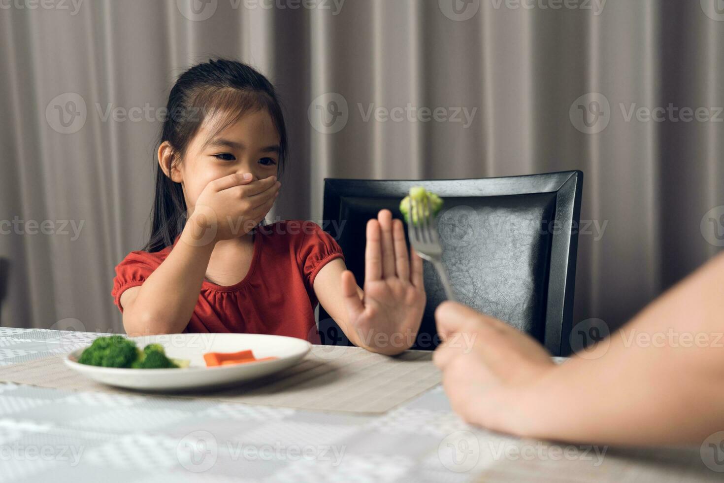 Little cute kid girl refusing to eat healthy vegetables. Children do not like to eat vegetables. photo