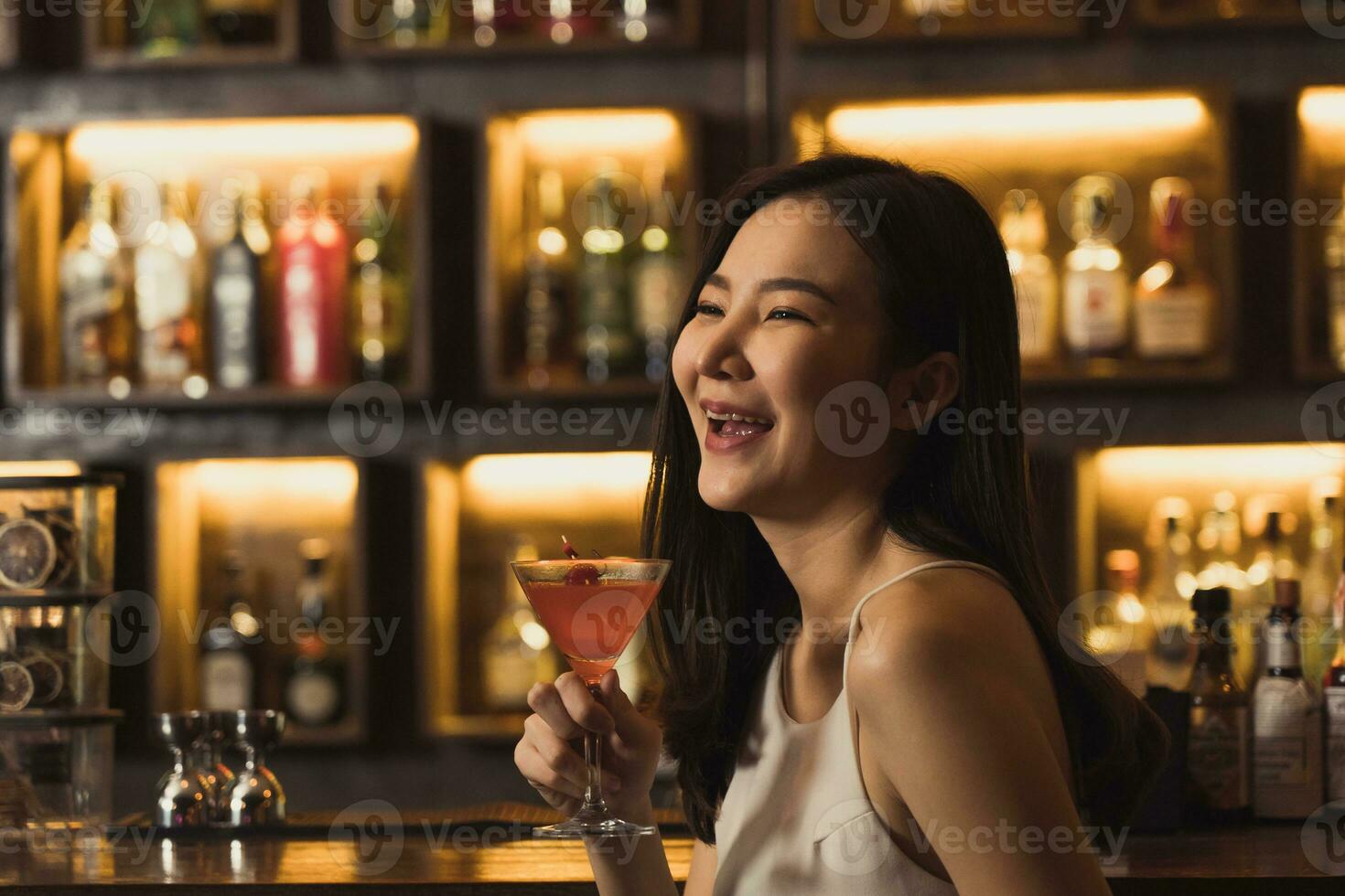 Asian women drinking cocktails and having fun at the bar at night. photo