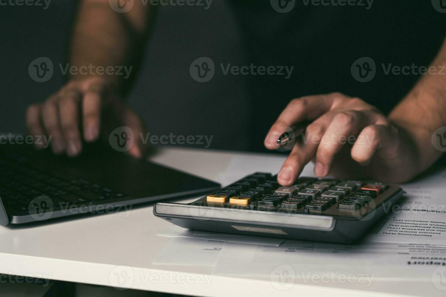 Asian man is using a calculator to calculate his monthly miscellaneous expenses at home. photo