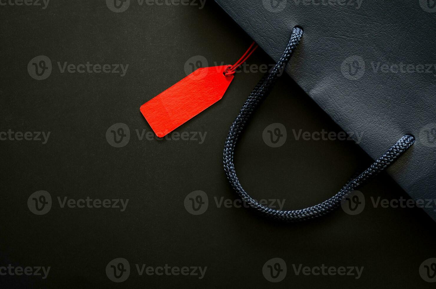 Dark blue shopping paper bag with blank red price tag for Black Friday shopping sale concept. photo