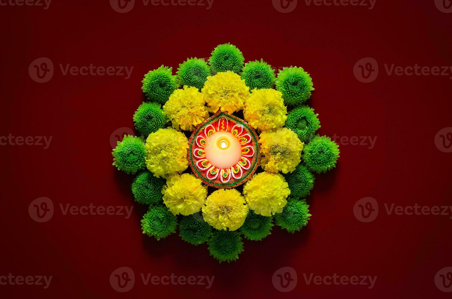 Clay diya lamp lits to celebrate for Diwali festival with colorful flowers on dark red background. photo