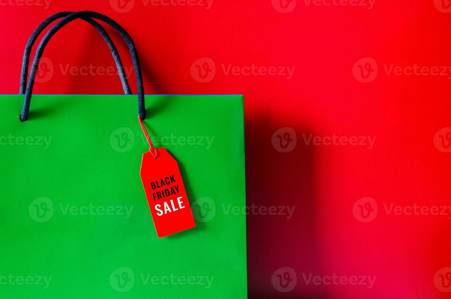 Green shopping bag with word on red price tag on red background for Black Friday shopping sale concept. photo