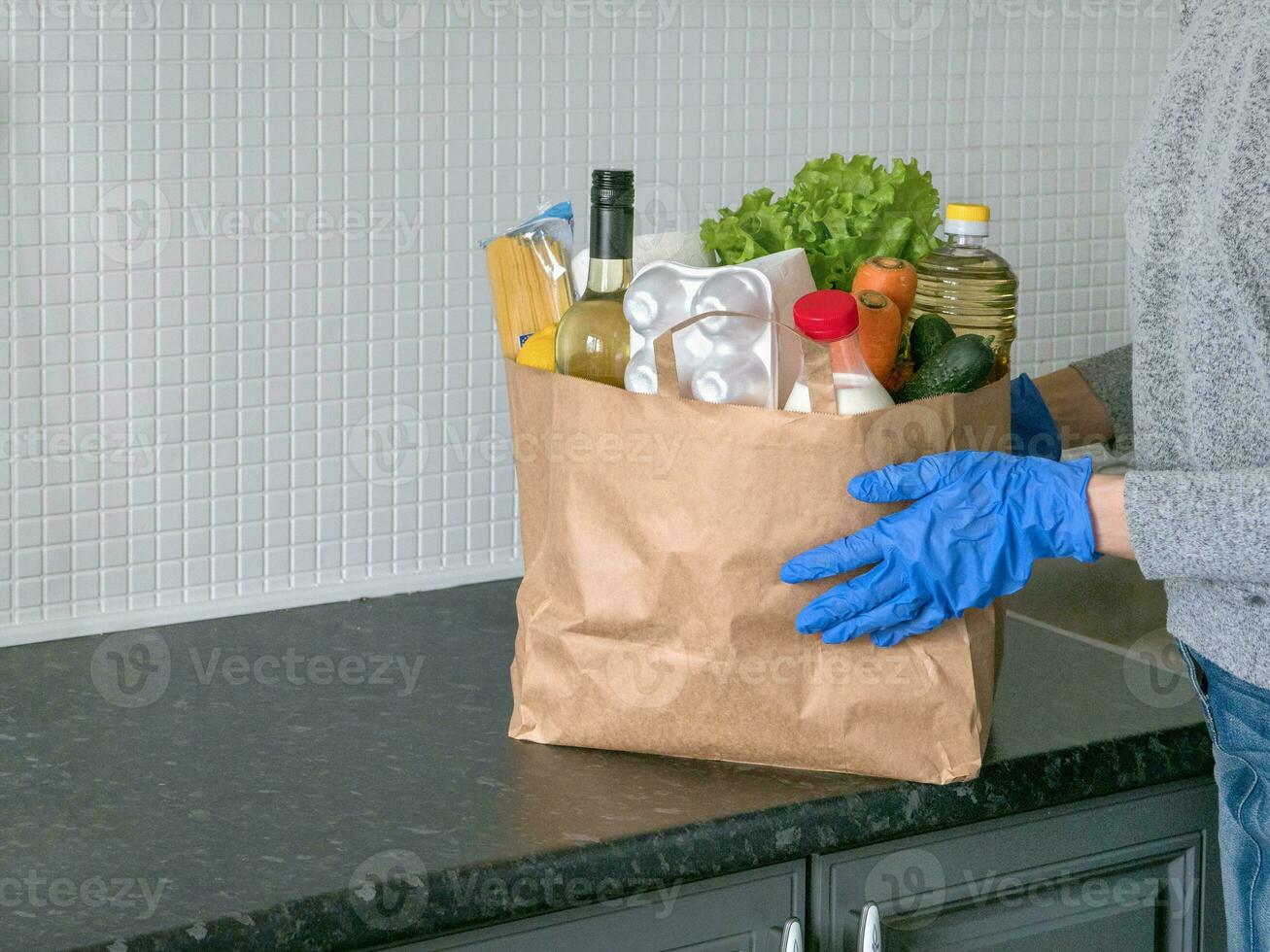 Safe home delivery. A package with products such as milk, eggs, vegetables and wine in a modern kitchen photo