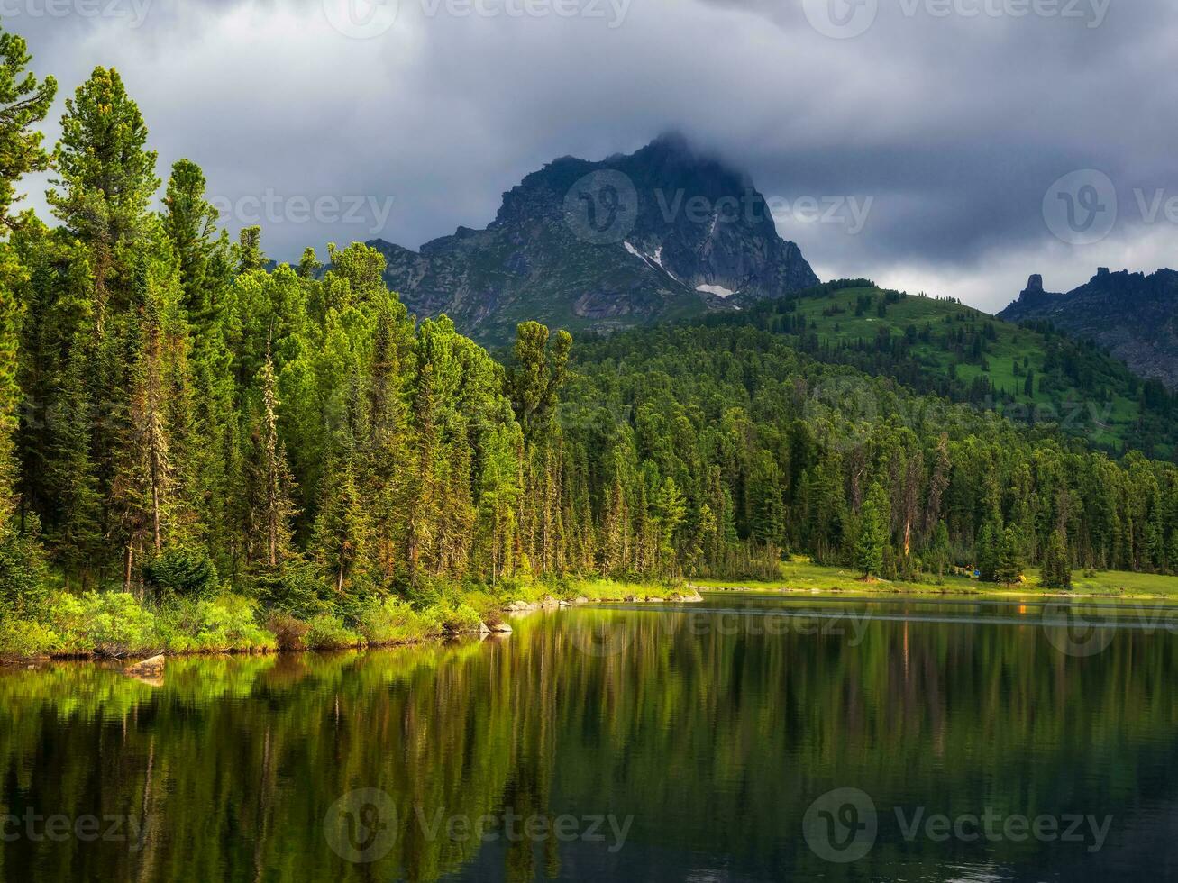 Lake Svetloye in Ergaki on an summer morning among the taiga rocks with blue sky in the warm sun and trees Mountain sunny landscape. photo