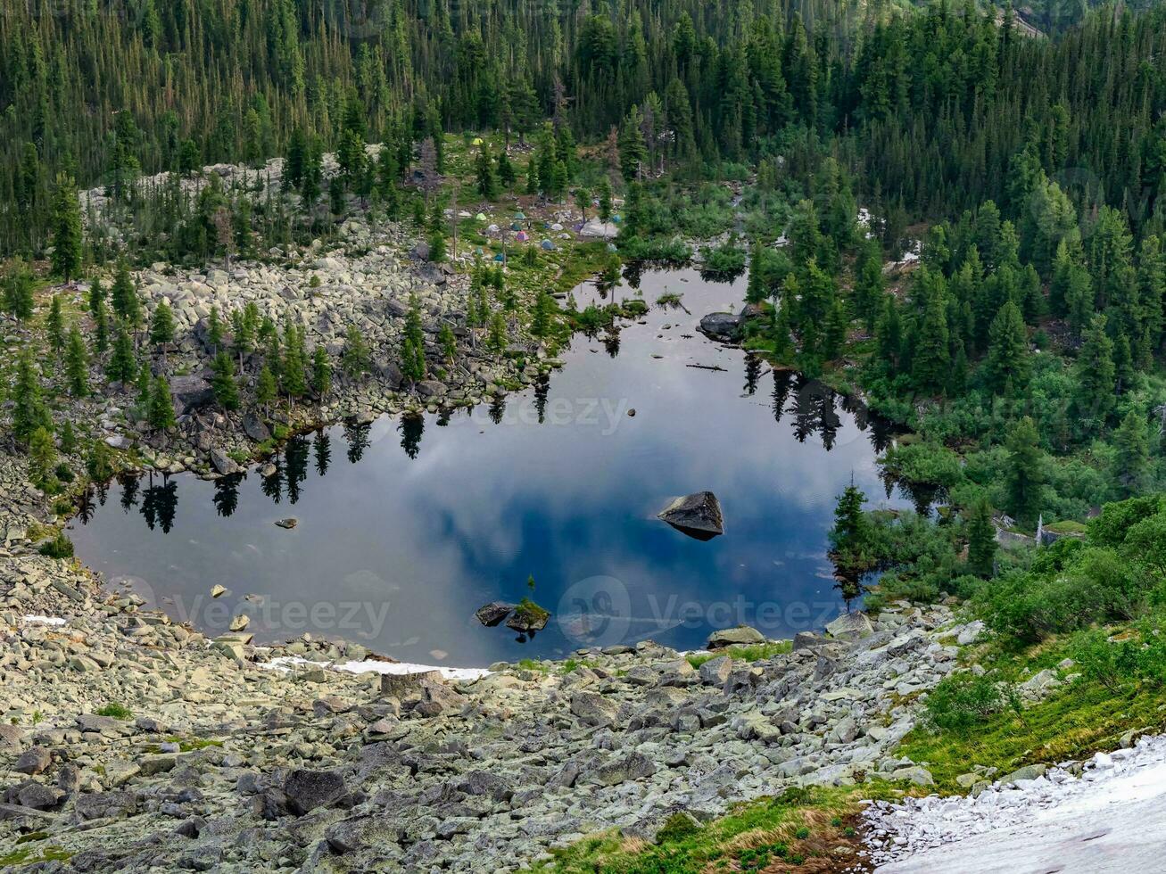 Aerial spectacular view to scenic valley with beautiful mountain lake, conifer forest and camp in mountains. Amazing atmospheric highland landscape. Wonderful majestic wilderness nature scenery. photo