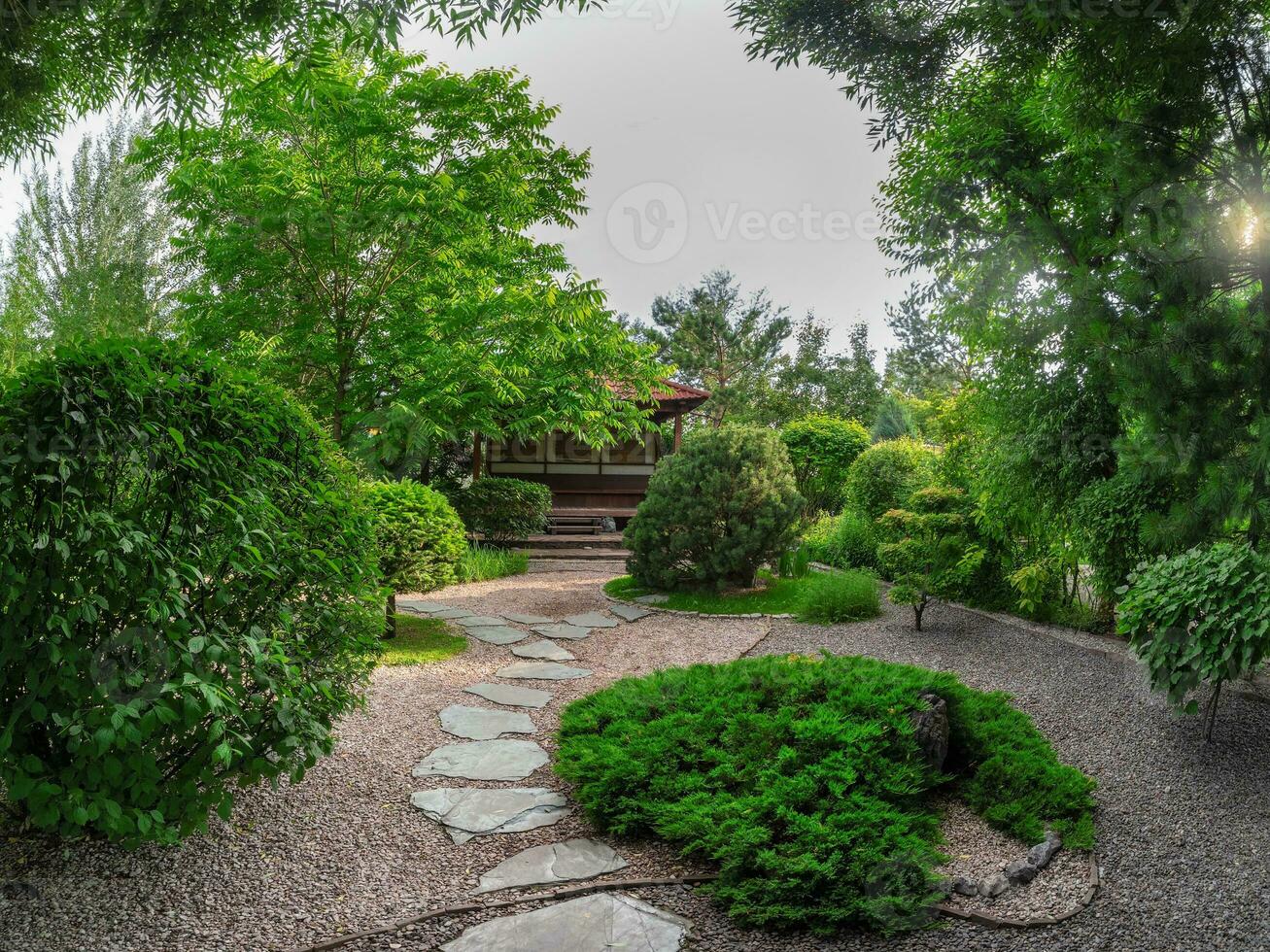 Small Japanese garden park style in spring with trees and wooden house on deep garden. The stone pathway to the house. photo