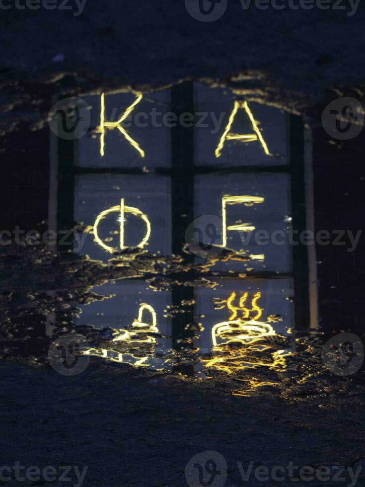 Bright fluorescent sign in Russian Cafe is reflected in a puddle on a wet night bridge. photo