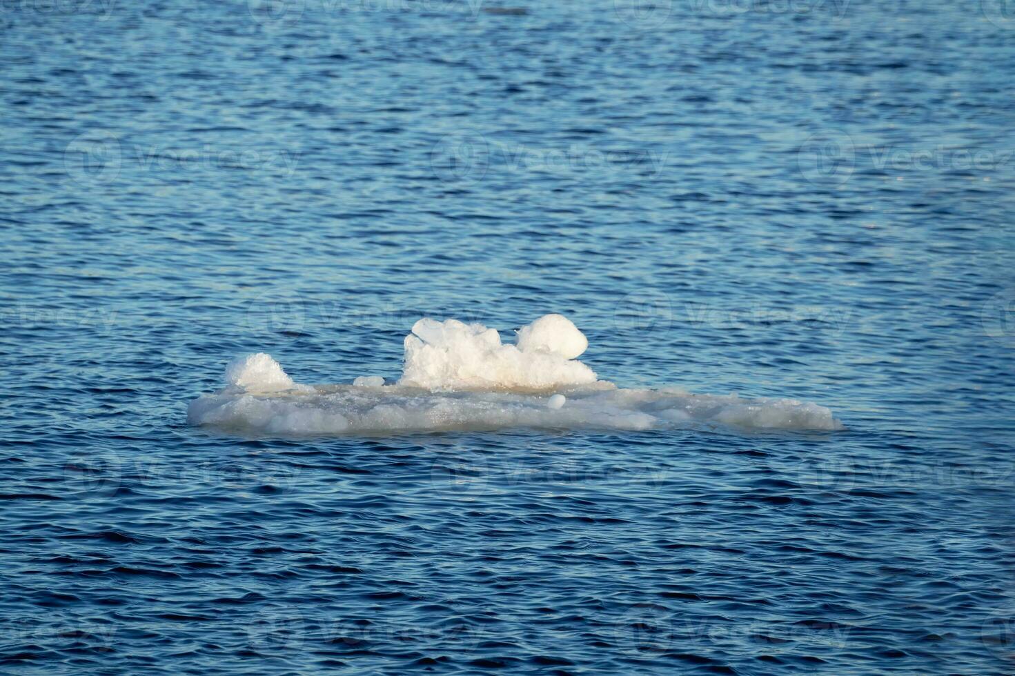 White iceberg of the remnants of ice floats on the blue water. The ice melts in the spring. Natural background. photo
