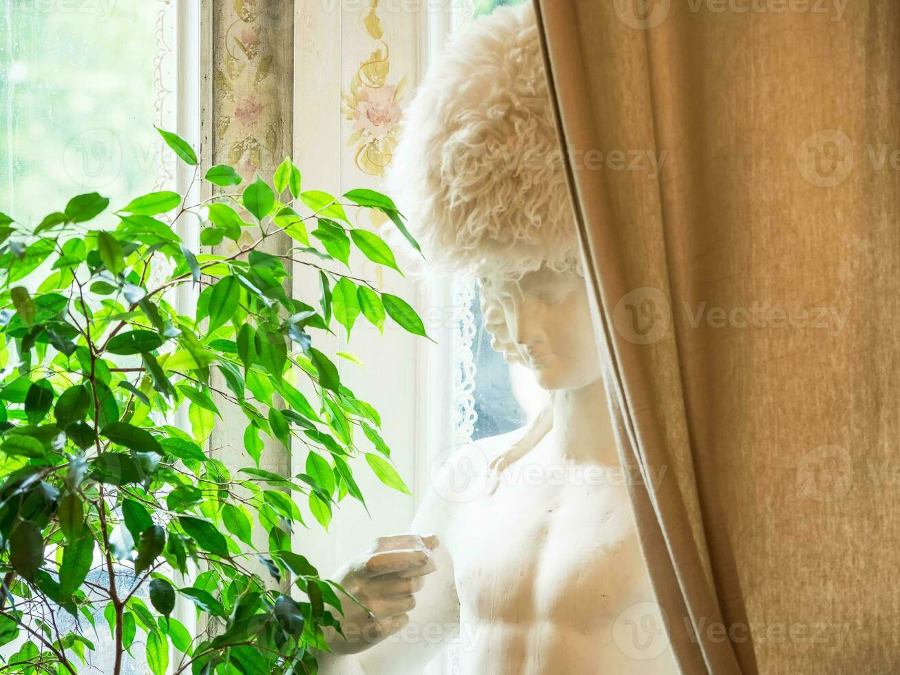 Bright authentic home interior. Plaster bust behind the curtain by the window, indoor plants. Home landscaping, urban jungle, biophilic design. Selective focus, close-up. photo