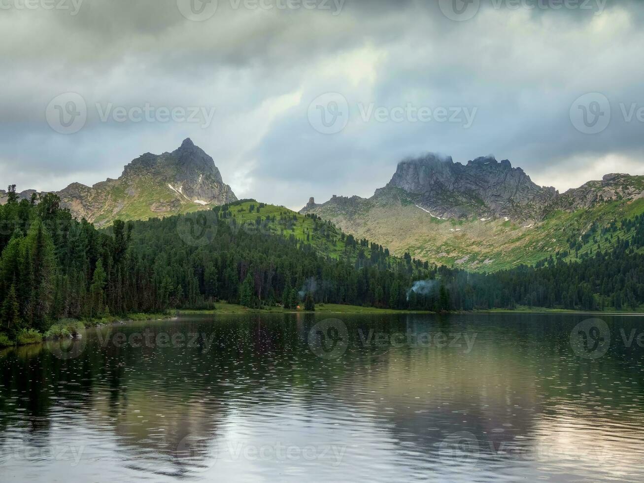 Amazing huge cloud above giant mountains. Raindrops on mountain lake. Wonderful droplets on lake water. Low clouds. Cloudy sky. Wonderful atmospheric ghostly highland landscape. West Sayans. photo