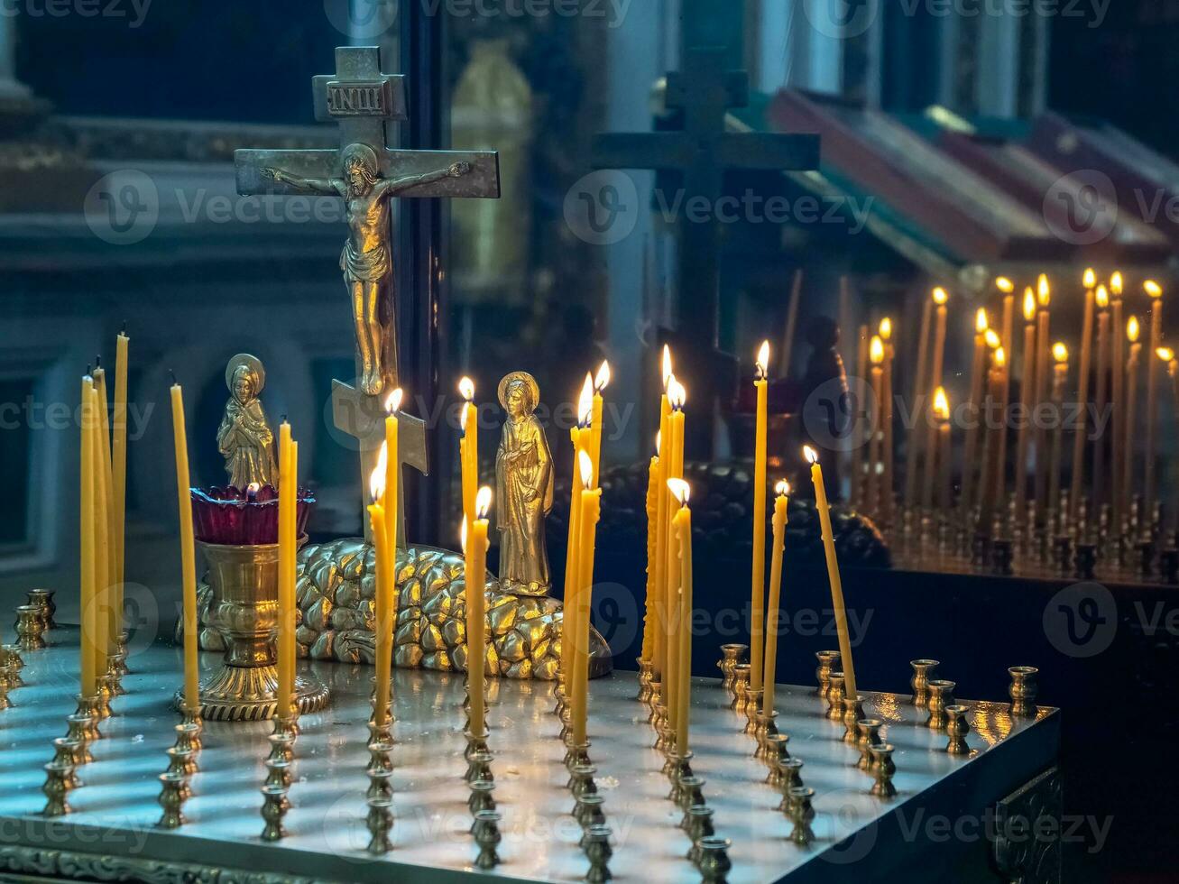 Church candles burn in front of a statuette of the crucifixion o photo