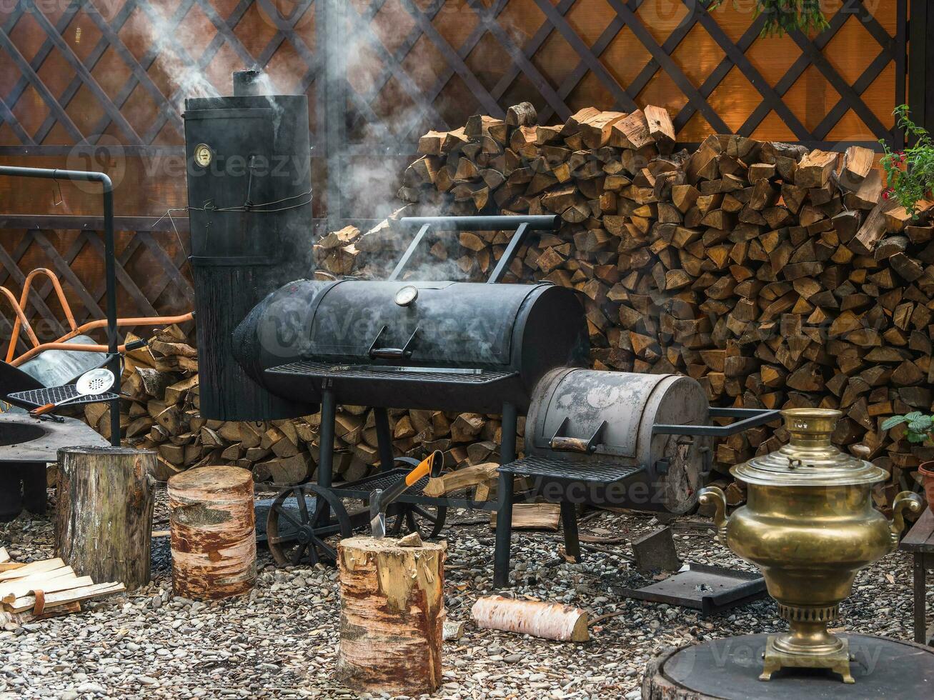 Big iron smokehouse with firewood stands on the courtyard. On the smokehouse, you can smoke various healthy foods. Small business smoking concept. photo