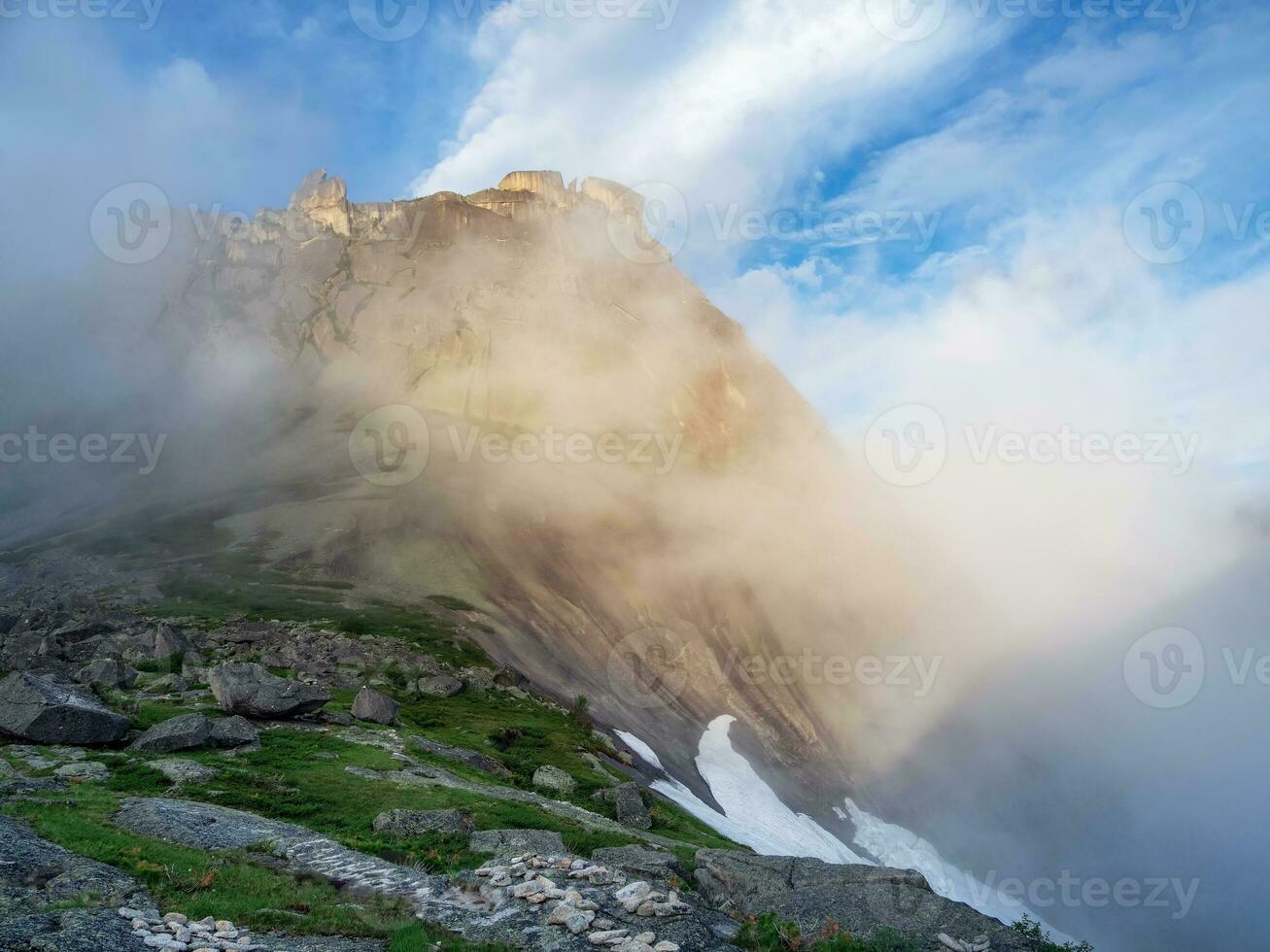 Soft focus. Sunrise in the mountains, in thick clouds. Light on the pass. The glacier is melting, illuminated by the bright golden morning sun. photo