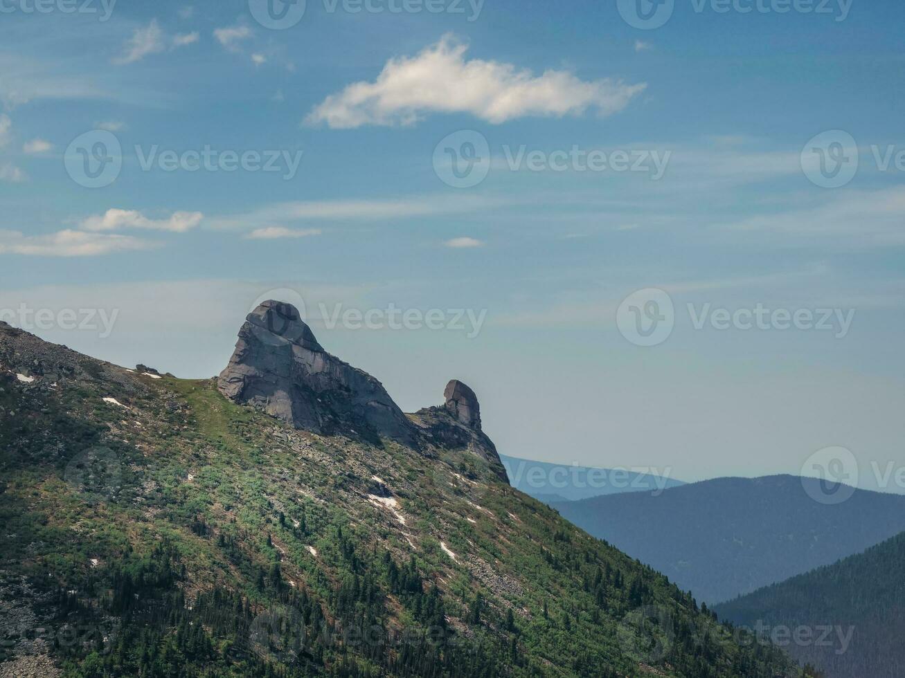 Minimalistic alpine scenery with diagonal great mountain ridge green forest and rocks under blue sky. Scenic sunny mountain landscape with high mountain range in sunlight. photo