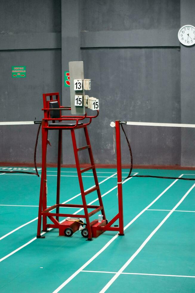 el bádminton del árbitro silla es rojo con un verde bádminton Corte antecedentes foto