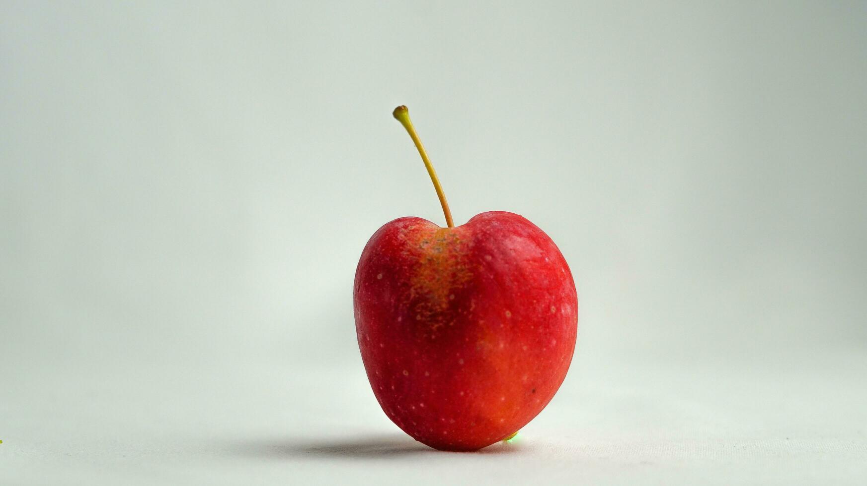 This fruit is called a strawberry apple, it tastes like an apple with a shape like a strawberry photo