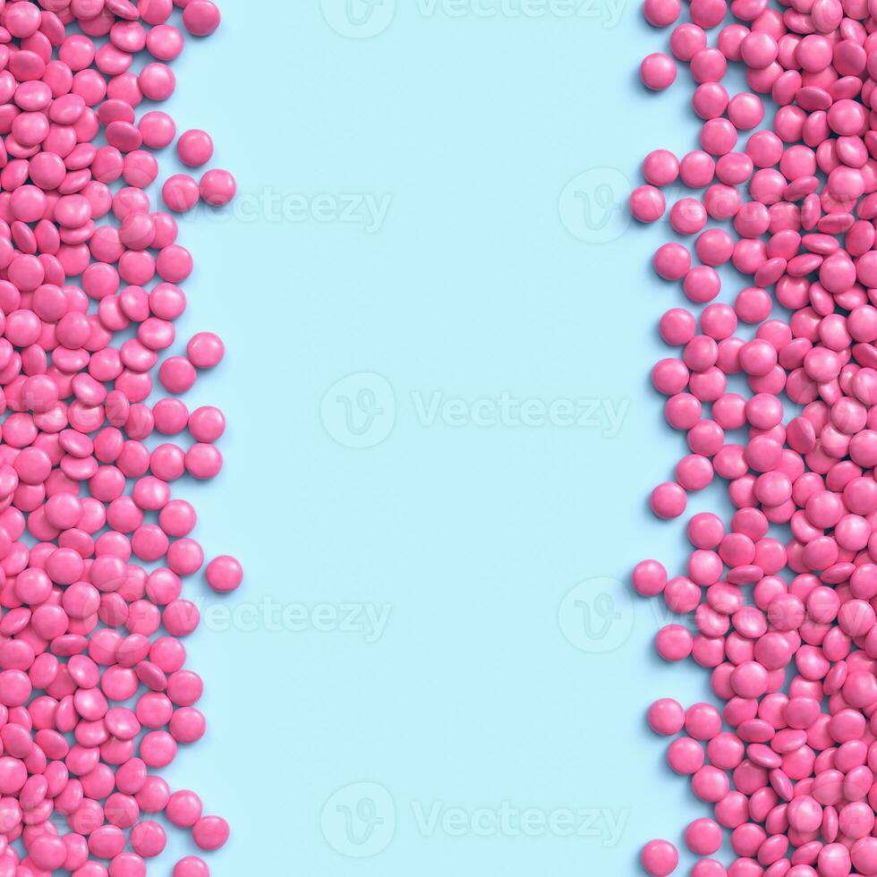 Double vertical border of pink coated chocolate candies on blue pastel background photo