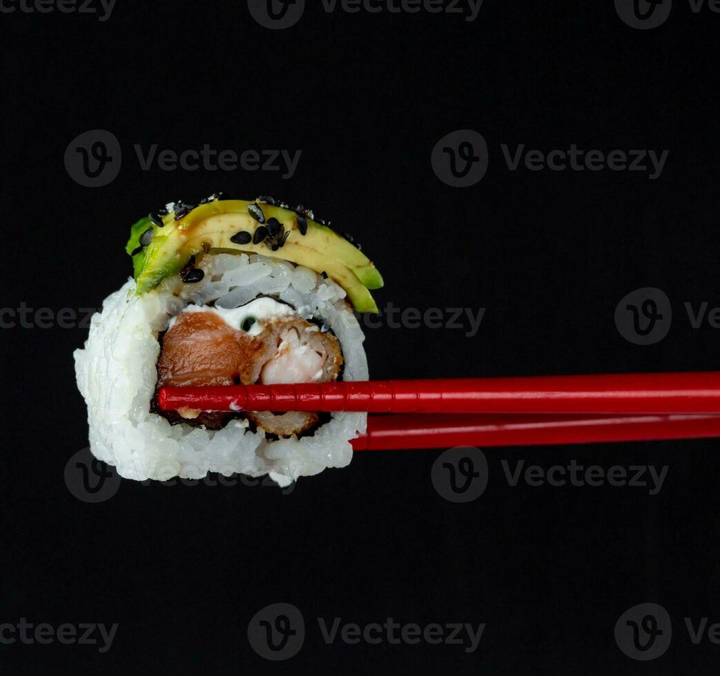 sushi on a black background with chopsticks, close-up photo