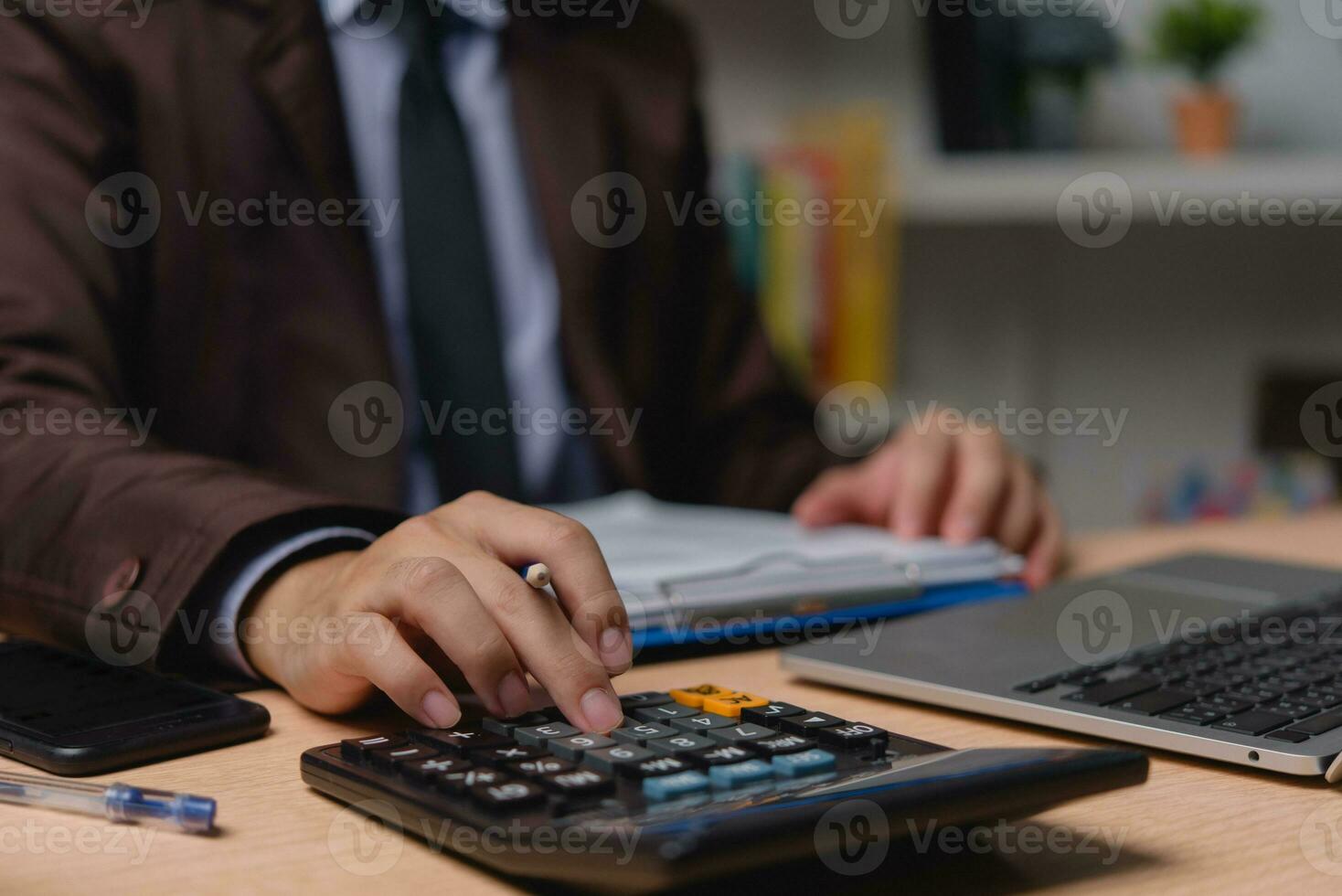 Businessman working on laptop and accounting financial marketing report document investment paperwork. hands of accountant using calculator to calculate tax refund economy. photo