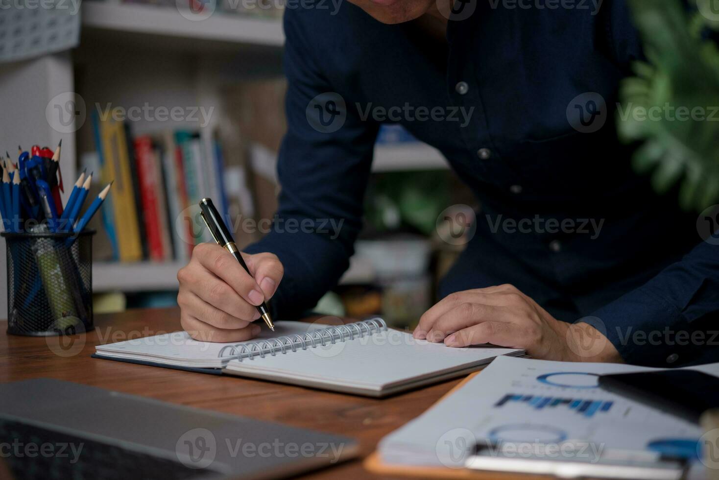 man hands with pen writing on notebook in the office.learning, education and work.writes goals, plans, make to do and wish list on desk. photo