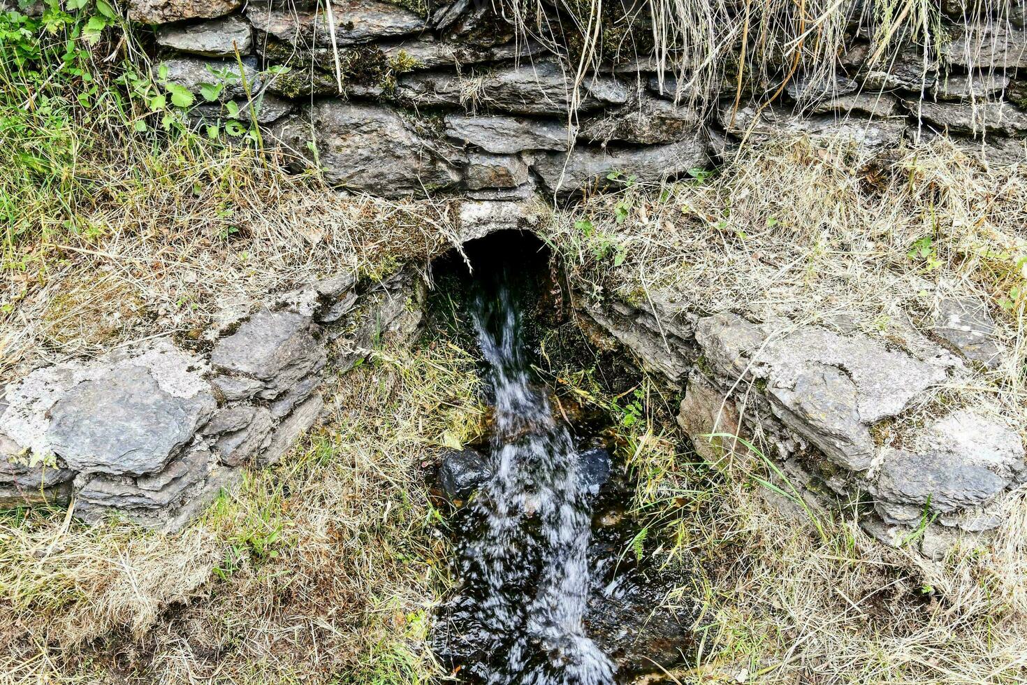 a small stream running through a stone wall photo