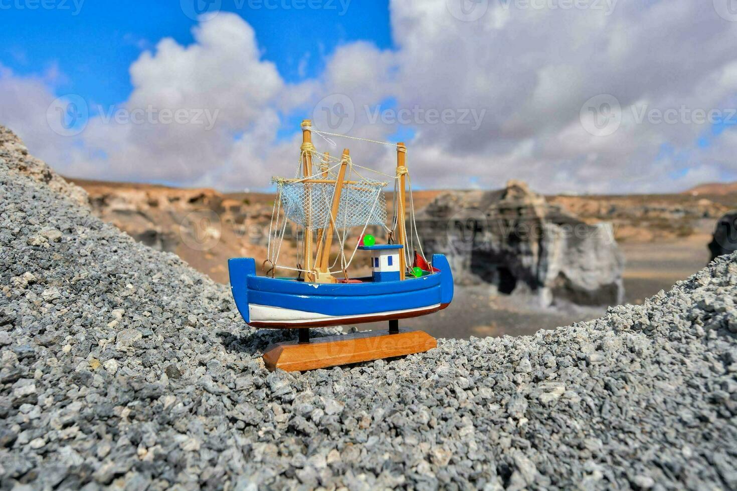 un pequeño juguete barco se sienta en parte superior de un rocoso acantilado foto