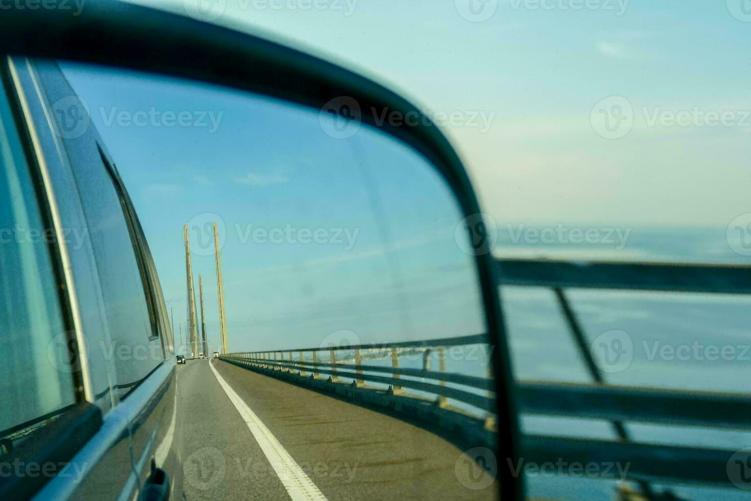 a car driving on a bridge with a side view mirror photo