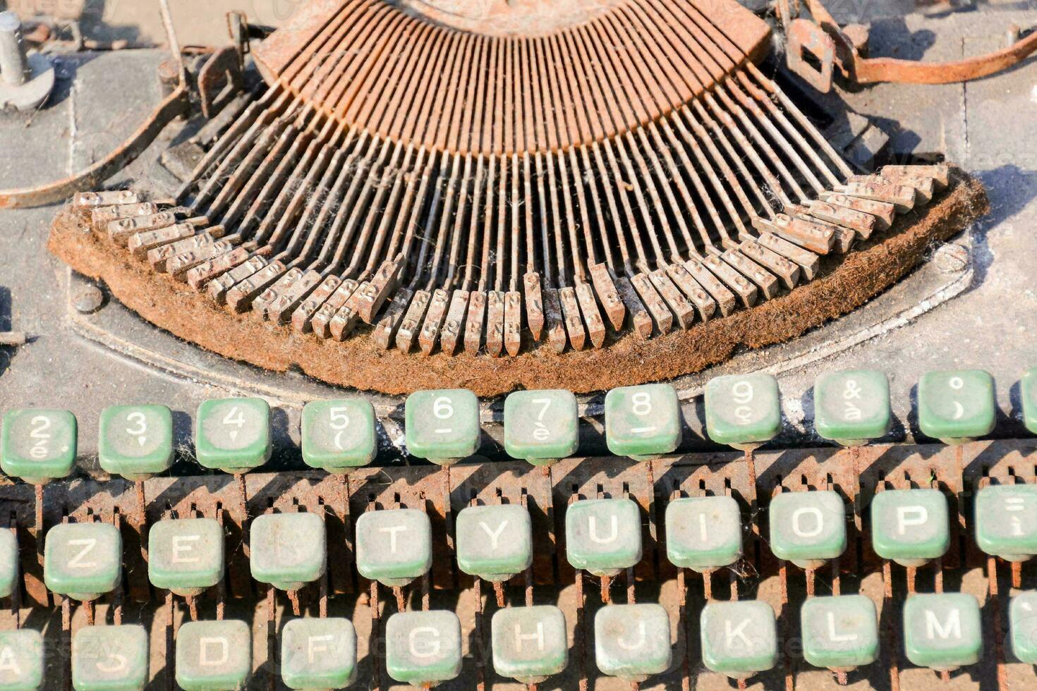 an old typewriter with green keys and a rusty metal frame photo