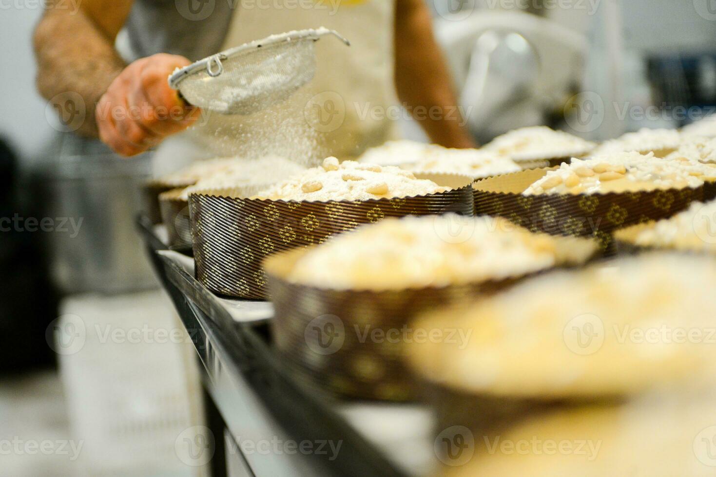 chef producing panettone, while lievitate, adding almond sugar topping to raw sweet bread. photo