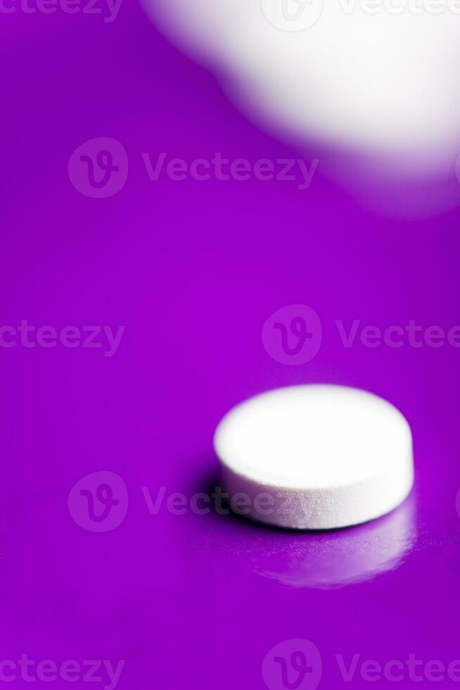 White pills over a solid lilac background with reflection. photo