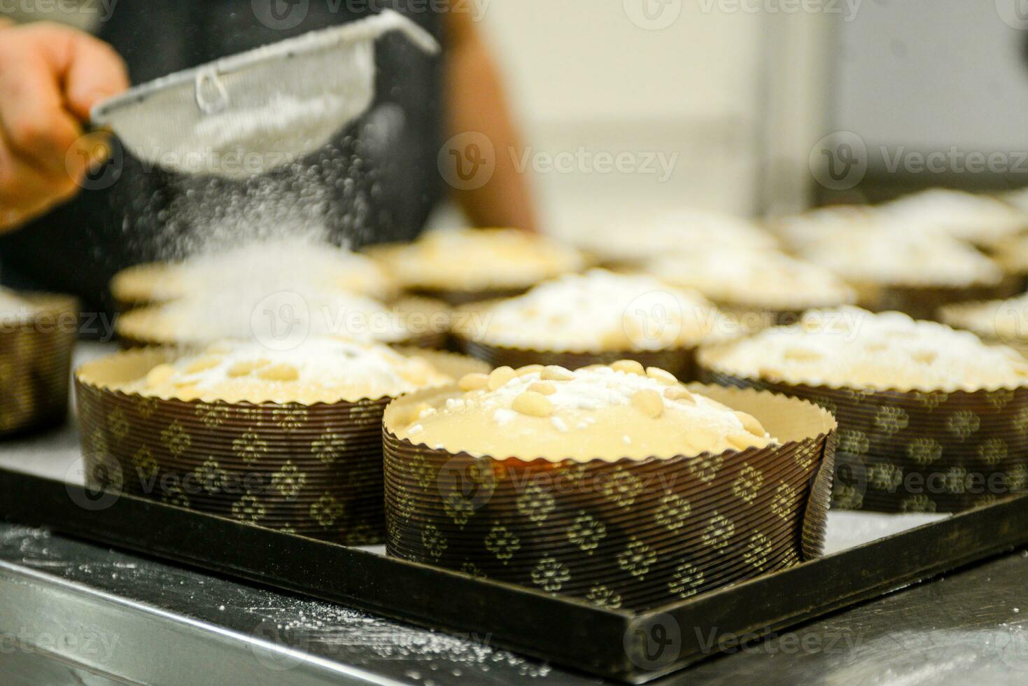 chef producing panettone, while lievitate, adding almond sugar topping to raw sweet bread. photo