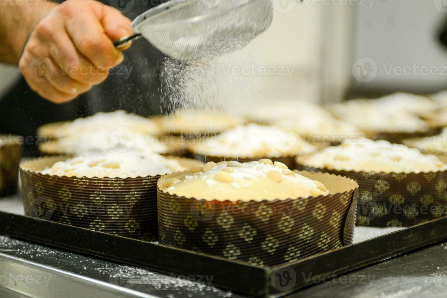 chef producing panettone, while lievitate, adding almond sugar topping to raw sweet bread. photo