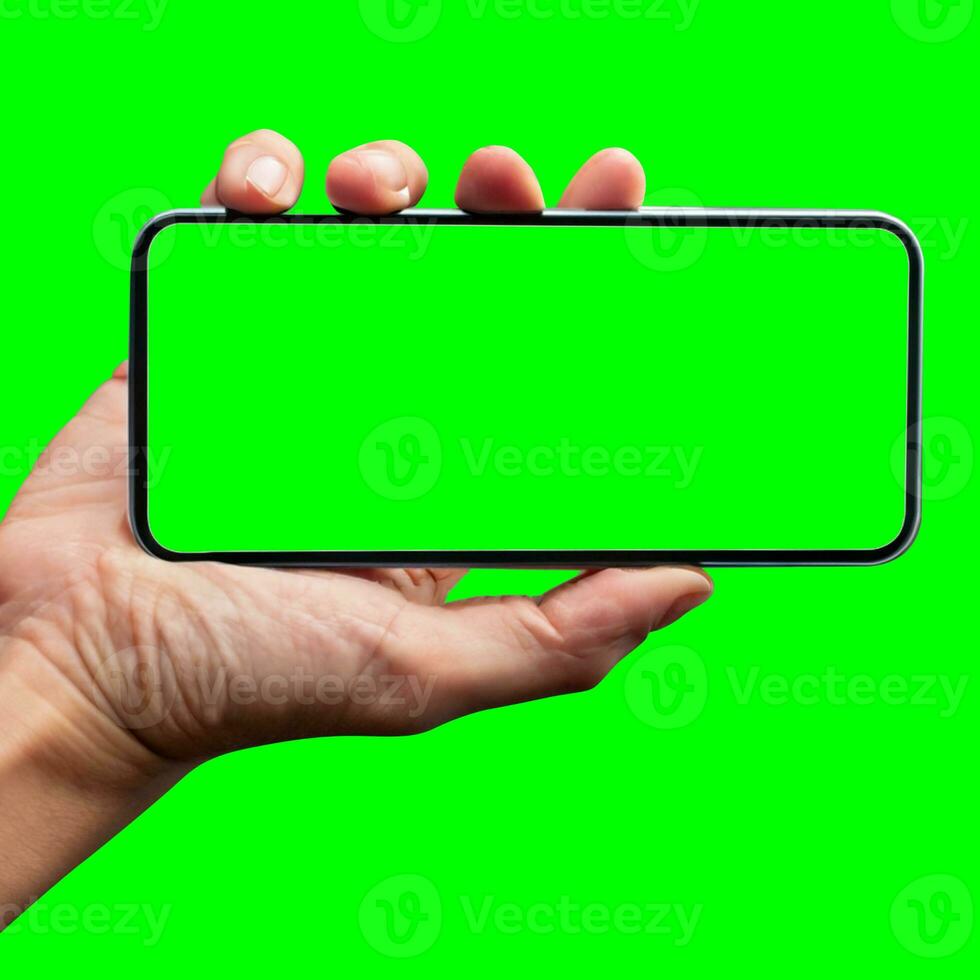 Image of hand holding a phone with a green screen in landscape orientation. on a white background. photo