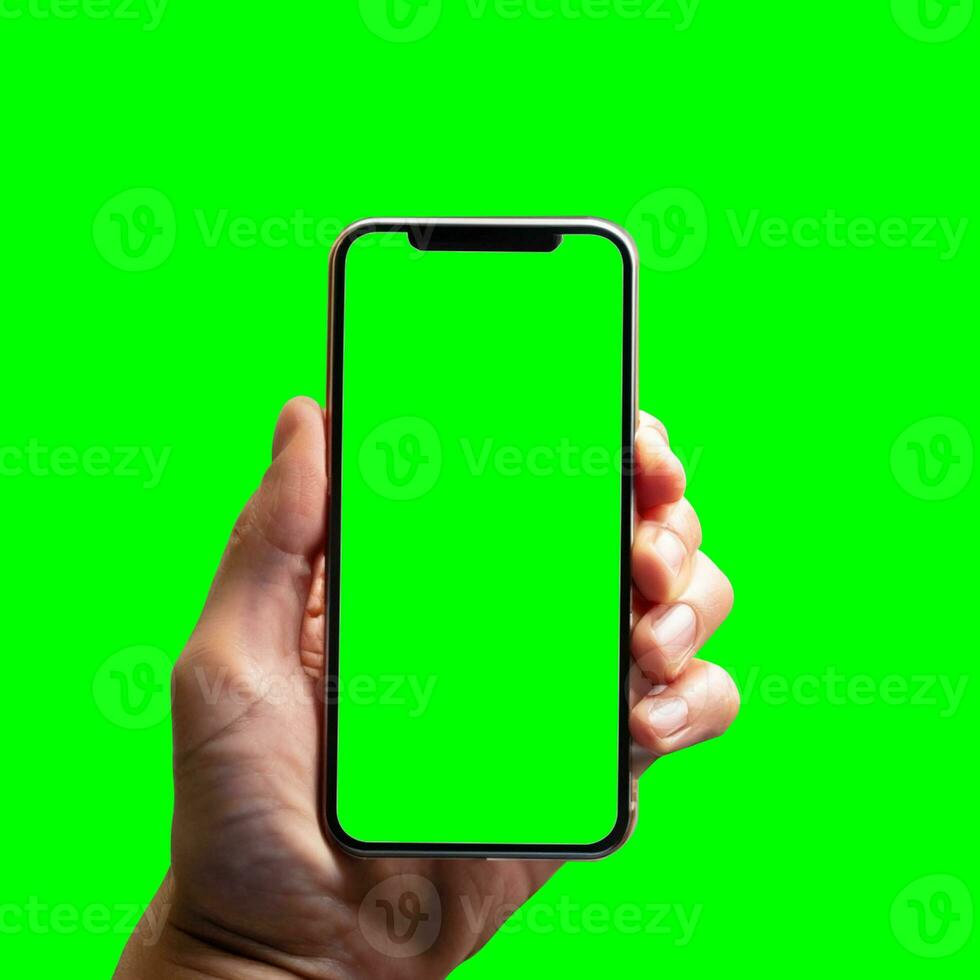 hand shows mobile smartphone with green screen in vertical position isolated on green background. Mock up mobile photo