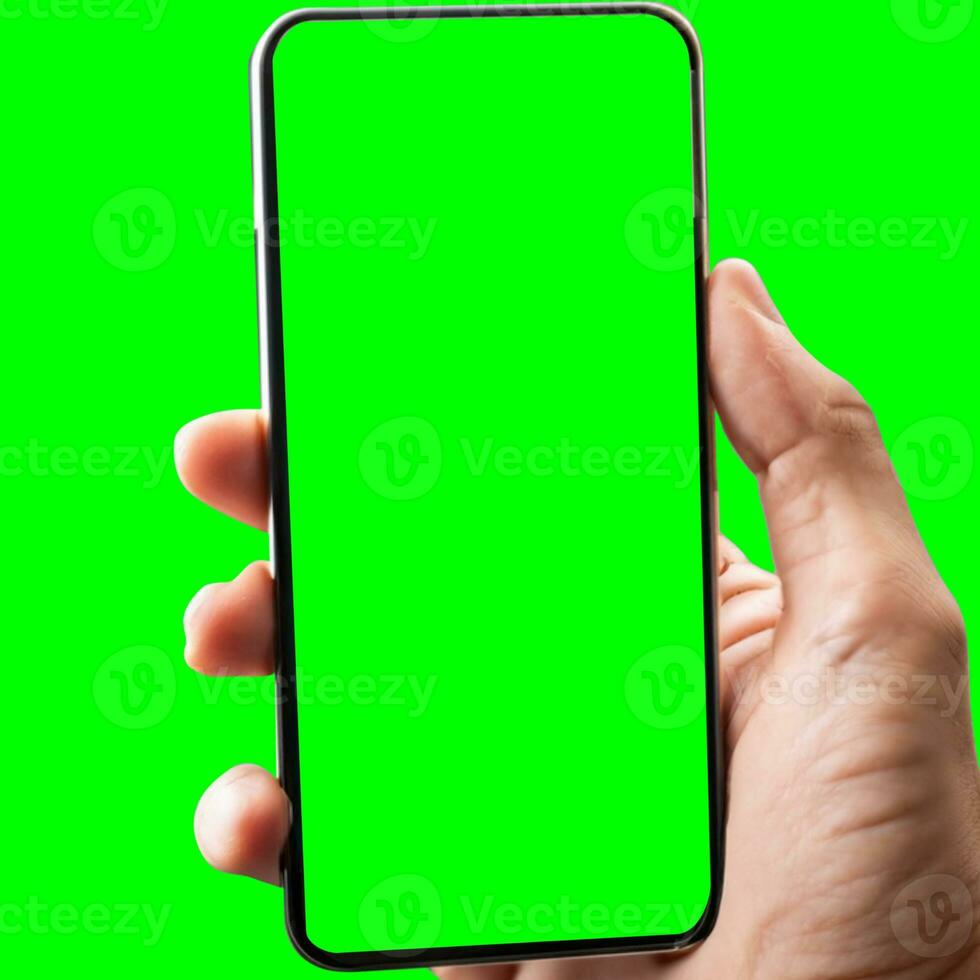 hand shows mobile smartphone with green screen in vertical position isolated on green background. Mock up mobile photo