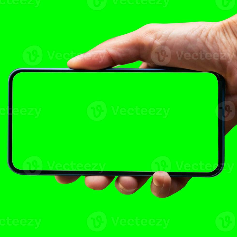 Image of hand holding a phone with a green screen in landscape orientation. on a white background. photo