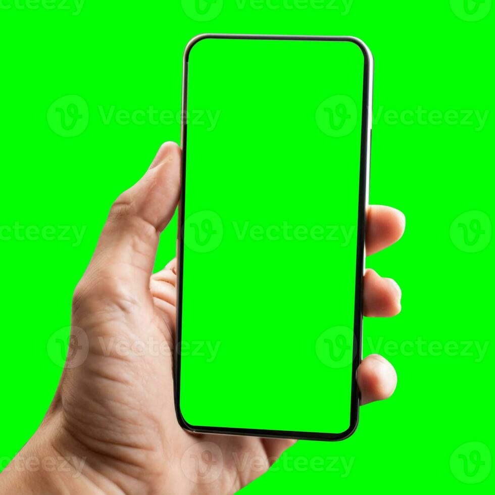 hand shows mobile smartphone with green screen in vertical position isolated on green background. Mock up mobile photo