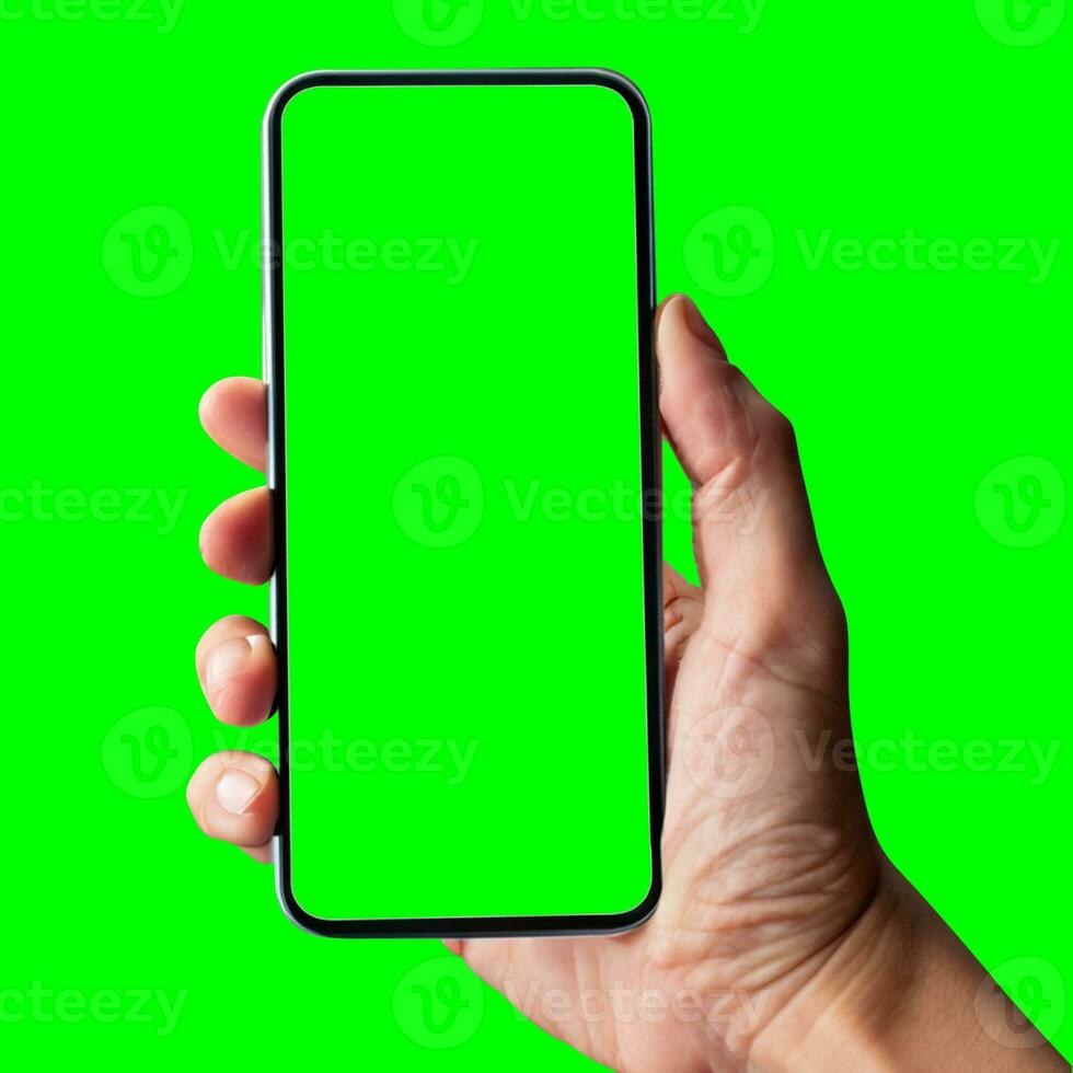 hand shows mobile smartphone with green screen in vertical position isolated on green background. Mock up mobile photo