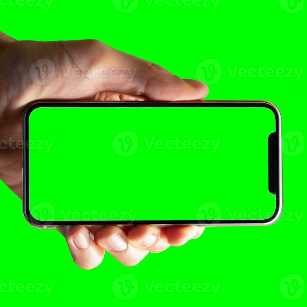 Image of hand holding a phone with a green screen in landscape orientation. on a white background. photo