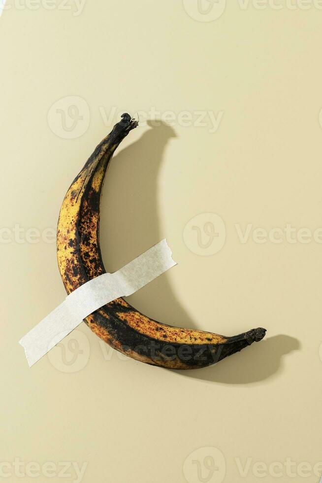 Long Over Riped Banana Duck Taped on Cream Wall photo
