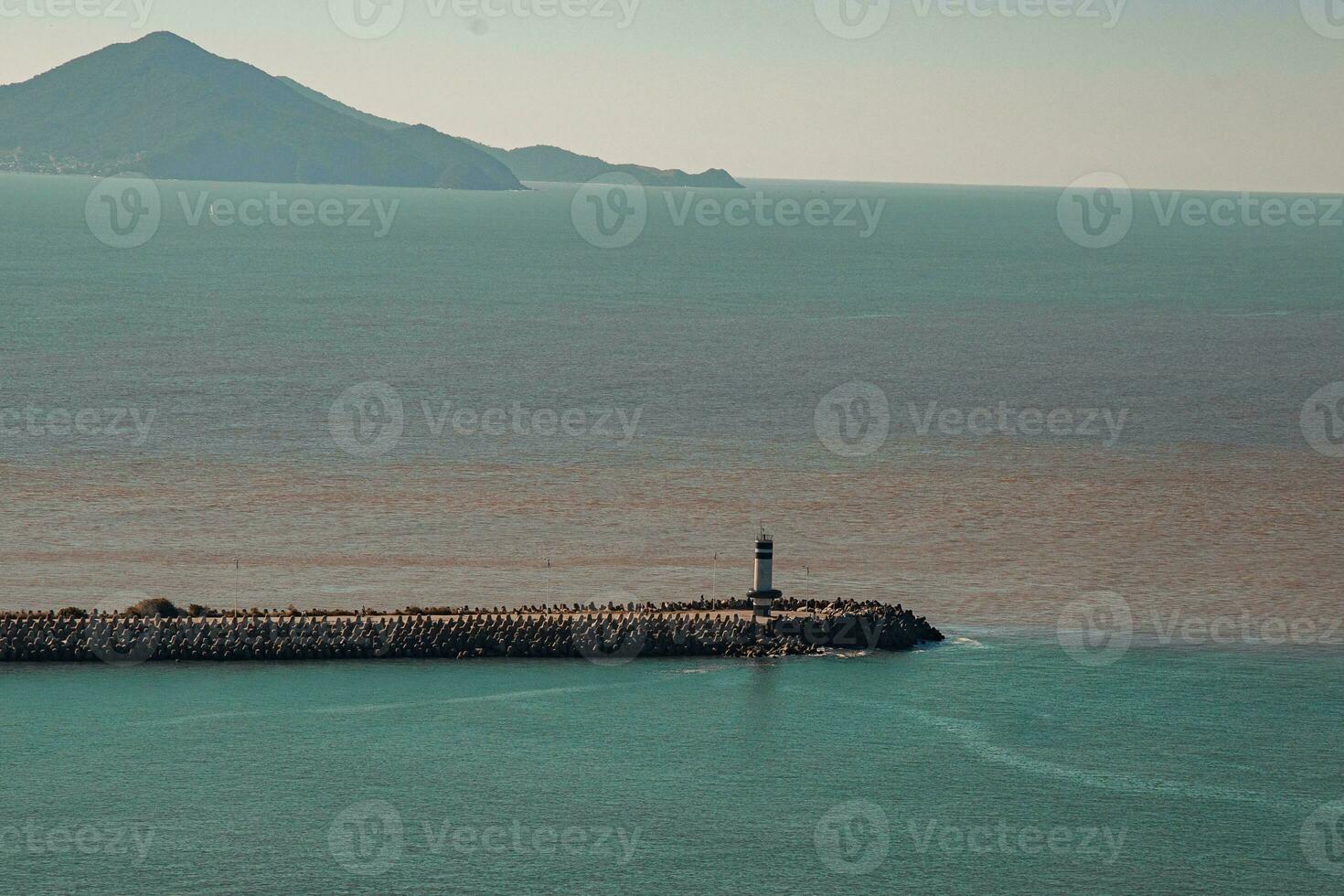 faro en el costa de el mar con montañas en el antecedentes foto