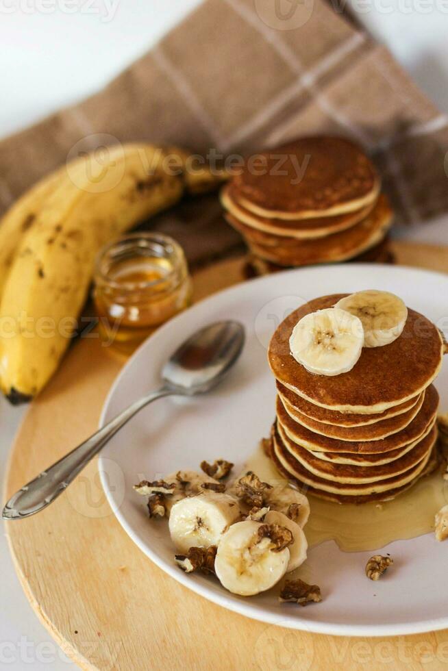 Homemade pancakes with banana, honey and walnuts on white plate photo