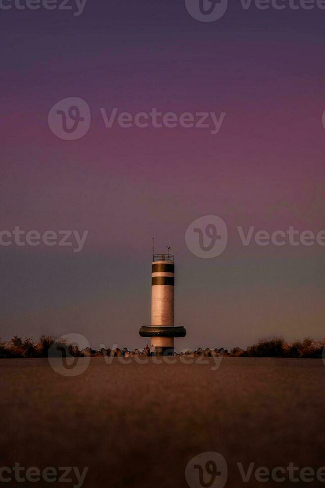 Lighthouse in the middle of the desert with purple sunset sky. photo