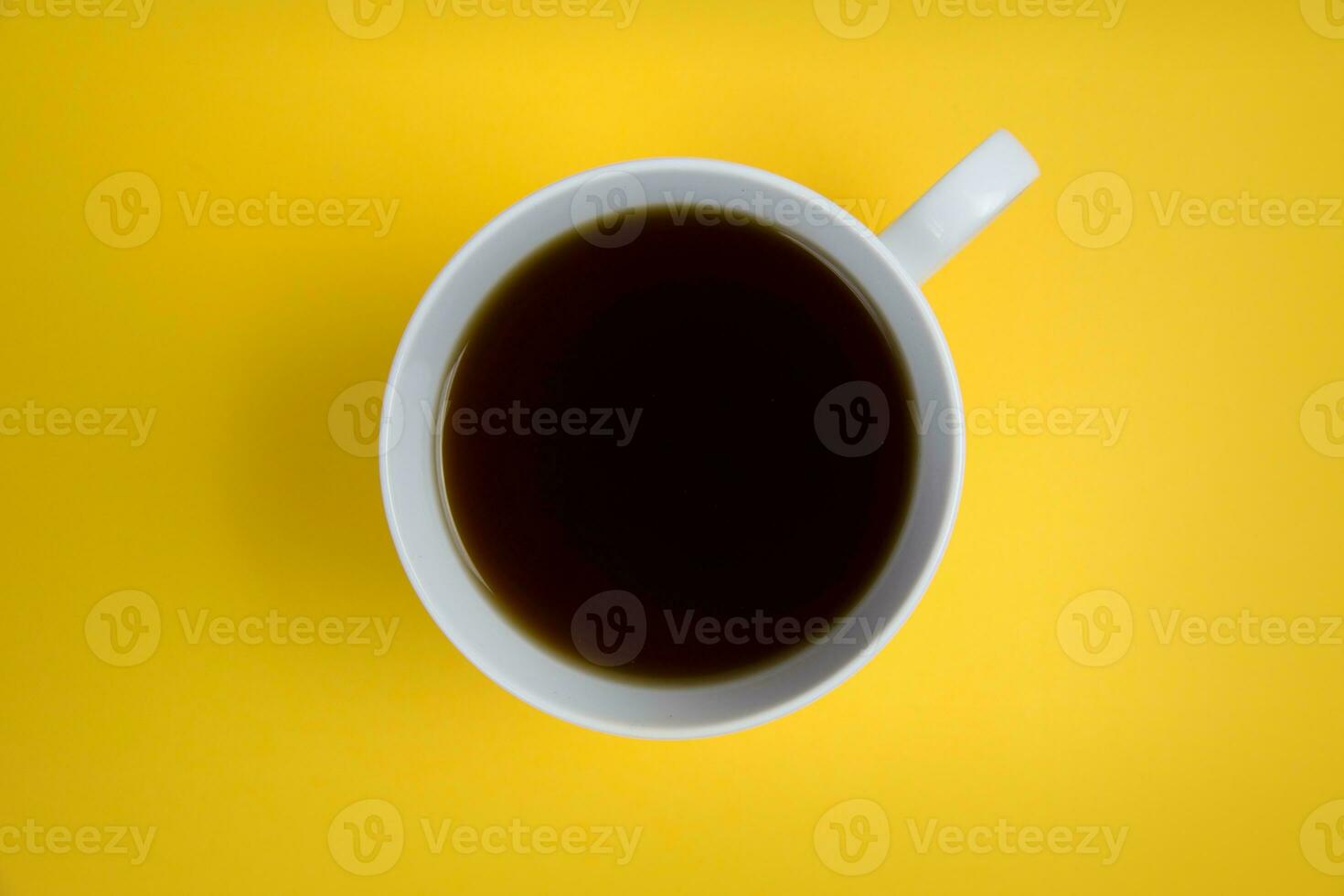 Cup of coffee on a yellow background. View from above. photo