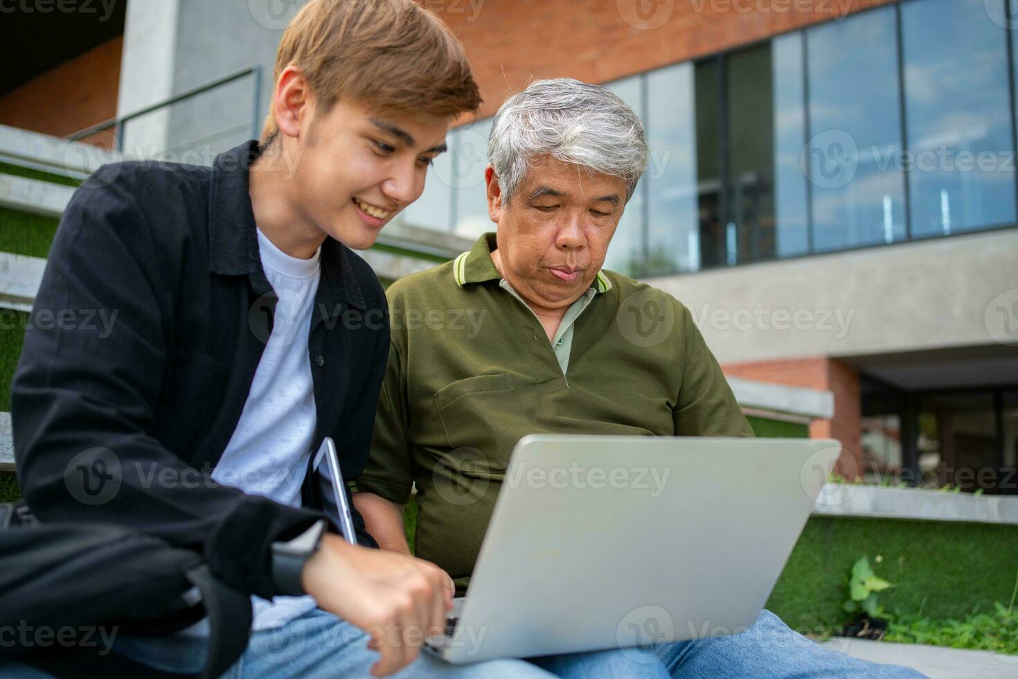 Focused young students listening old senior aged teachers for advise capstone project in university. Happy middle aged teacher working together with students for graduation project. photo