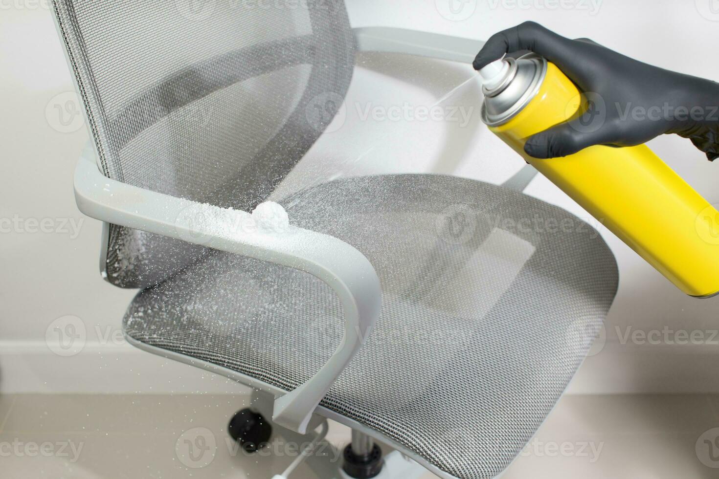 A man cleans the chair armrest with a sprays foam cleaner. photo