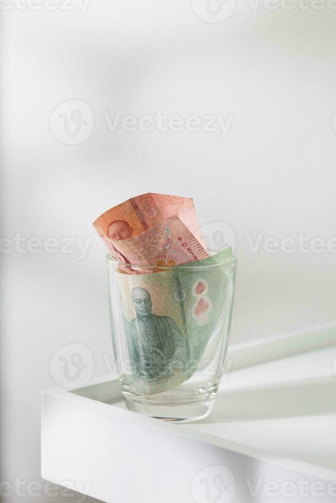 Tip money in a glass on a white dining table. photo