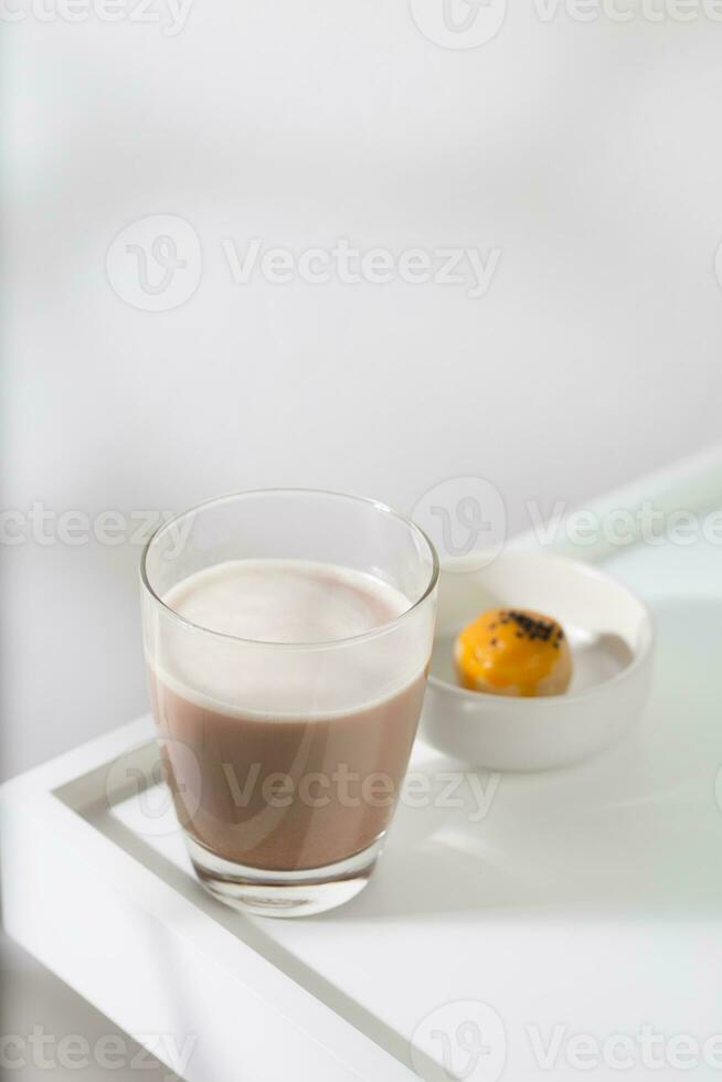 Hot cocoa in a clear glass on a white wooden table. photo