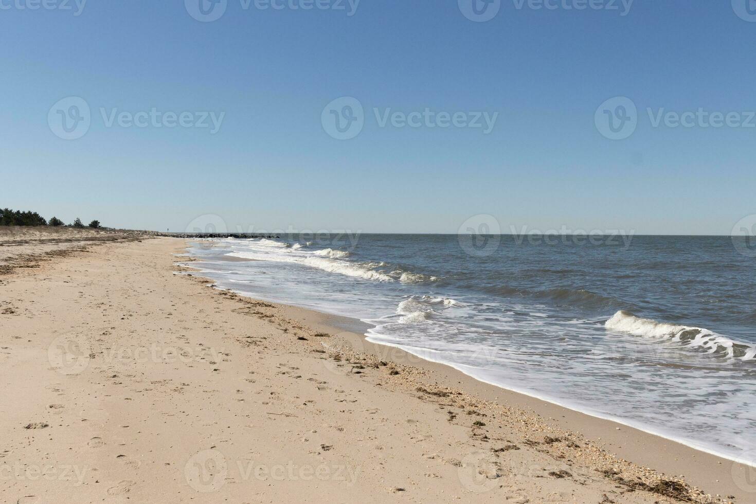 I loved the look of this beach scene as the waves crashed in. The pretty look of the whitecapped surd rushing in to the shore. The sand showing different tone to where the water once was. photo