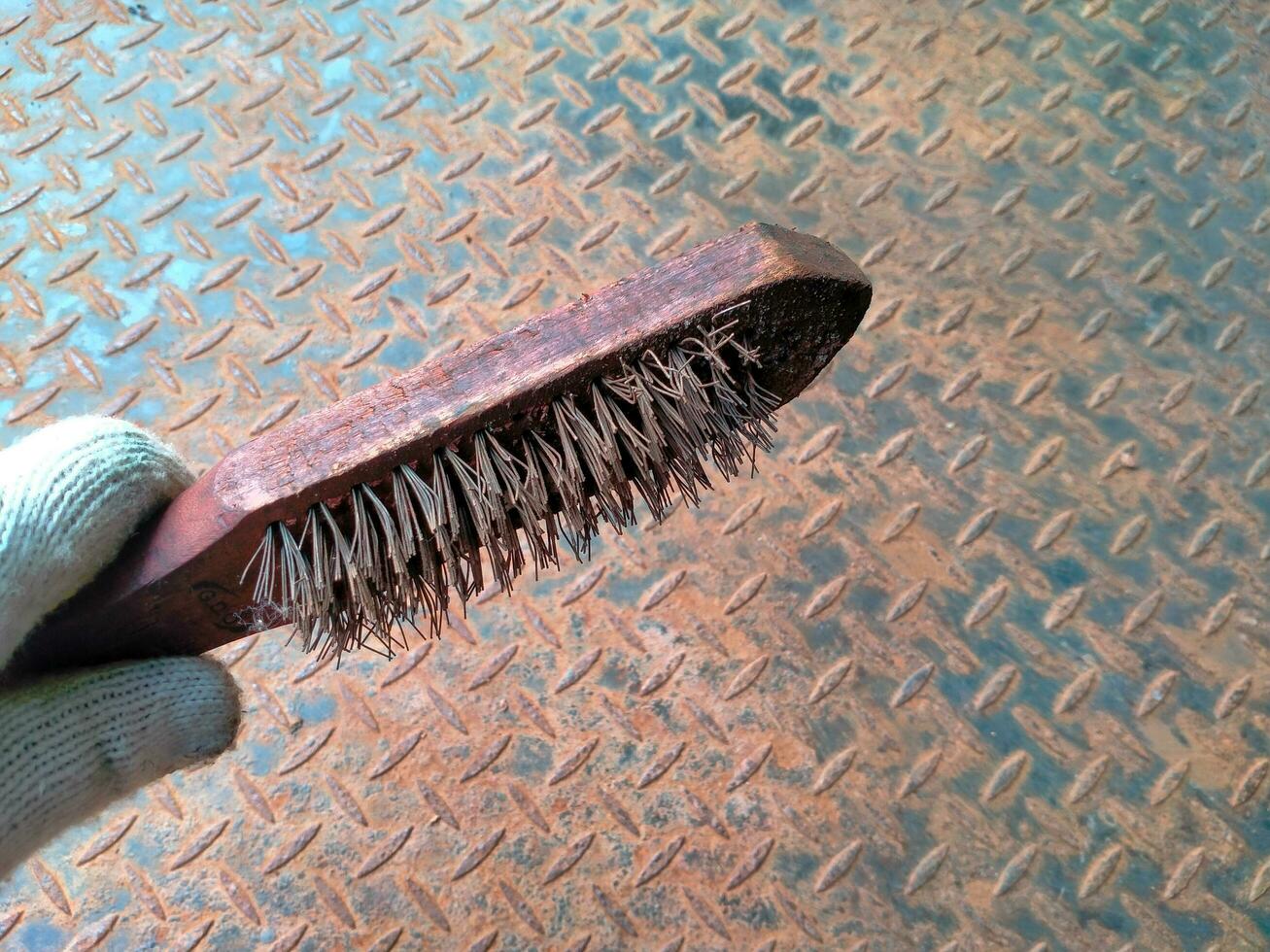 Rustic old Steel wire brush tool on a corroded iron textured background. Tools to clean metal from corrosion photo